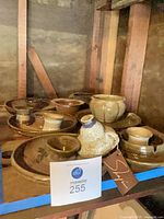 Shelf view showing majority of pottery pieces including plates, bowls, mugs and pitcher
