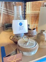 Group view showing tall bottle vase, lidded jar, tray, bowls