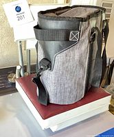 Grey soft-sided cooler tote front view on top of folded seats, showing logo and strap