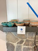 Full group of eight turquoise pottery pieces on mantle