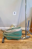 Overall view of Compact Electra vacuum with hose, wand, brush head, small nozzle and filters