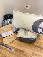 Group shot of pillow, fleece throw, mattress topper, blanket, duffel