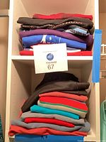 Two stacks of folded women's t-shirts and tops on shelving unit