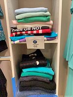 Two stacks of folded women’s tops on shelving