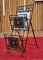 Front view of folding magazine rack displaying pressed tin panels and scrolled metal frame