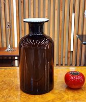 Front view of brown cased glass vase beside reference object