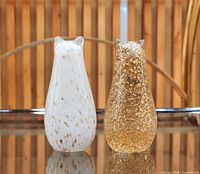 Front view of both glass cat figurines, white speckled and gold fleck versions