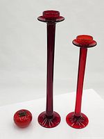 Pair of red art glass candlesticks standing, comparison size object nearby