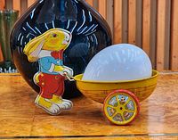 Left side view of pressed tin bunny pushing cart with egg