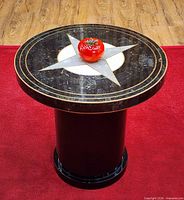 Entire side table showing granite top with compass rose inlay and cylindrical black lacquer base