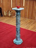 Full view of teal-green carved stone pedestal with removable square top and octagonal base