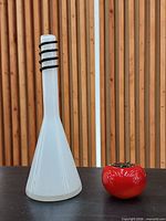 Front view of white art glass bottle vase beside red object for scale