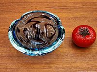Top view of blue heavy art glass ashtray bowl beside tomato for scale