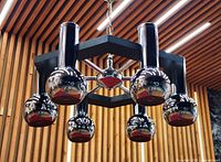 Full view of chandelier hanging, showing chrome orbs and black hexagonal frame