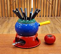 Complete fondue set on table: pot, stand, burner, forks visible