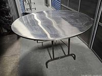 Top view showing circular stainless steel surface and folding base