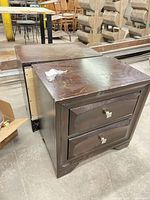 Two dark brown wooden bedside tables side by side showing drawers and surface