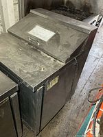 Angled view showing stainless body, lift lid, casters, and power cord