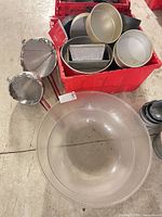 Overall lot showing large plastic bowl, strainers, red crate with pans