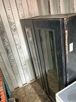 Overall view of black woodgrain two-door fridge inside container