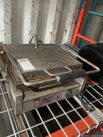 Closed sandwich press on shelf showing exterior and control panel