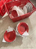 Red bowls and plates stacked; basket with white and red plates visible