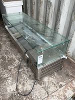 Full view of stainless countertop display with glass cover and power cord