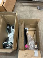 Two boxes containing pair of black wall sconces and packaged brass flex arm light
