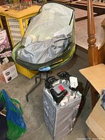 Collapsed playard in carry bag with collapsible bassinet/canopy on table