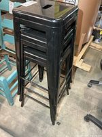 Three stacked black metal bar stools front view