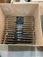 Partitioned carton holding stacked black plastic modelling bases