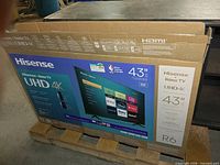 Factory box showing Hisense 43" UHD 4K Roku TV on pallet