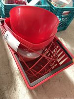 stack of red plastic bowls and wire fruit basket in crate