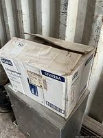 Damaged but sealed shipping box labeled Tork Dispenser AutoFoam 572028A