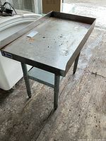 Full view of stainless table showing top, legs, and surrounding area
