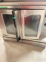 Full front view of SunFire stainless steel oven showing door, handle, glass window, and lower panel