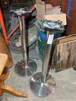 Two chrome-plated cast iron bar-height table bases standing upright