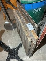 Stack of six rectangular wood table tops leaning against other items