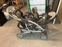 Full side view of Graco tandem stroller showing dual seats, frame and wheels