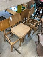 Group of six wooden chairs with loose seats stacked on top