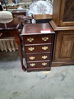 Front view of dark wood two-drawer file cabinet with brass pulls