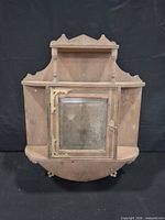 Front view showing cabinet, glass door, shelves and decorative crest