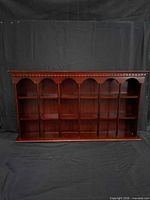 Front view of wood wall shelf showing compartments and cherry finish