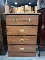 Front view of four-drawer brown chest with brass-tone hardware