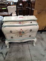 Front view of painted bombe chest with floral motif and two drawers