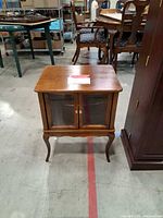Front view of wood curio side table with glass doors