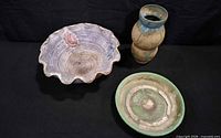 Overhead view of three ceramic items: scalloped bowl, plate, vase