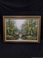 Full view of framed landscape painting showing bridge, forest, frame