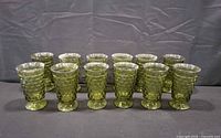 Row of twelve green footed textured glass cups front view