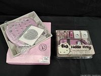 Heart-shaped pink TV remote in tray next to sealed Hello Kitty accessory kit
